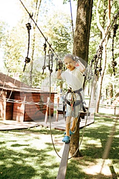 Little boy climbs in rope park at sunny day