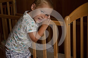 Little boy climbs the side in the crib