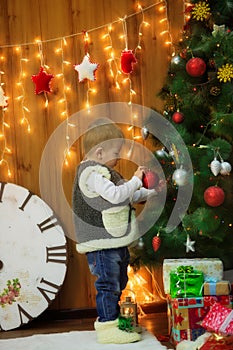 Little boy with a clock and gifts at the Christmas tree