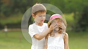 Little boy closes his eyes to the girl with his own hands. Slow motion