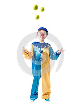 Little boy in clown suit juggling three balls and smiling