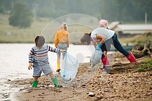Little boy collecting garbage with group of kids