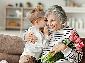 Little boy congratulating grandmother with flowers photo