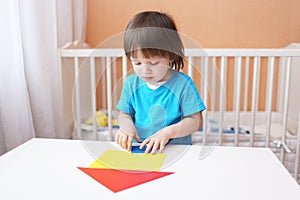 Little boy constructing house of paper details