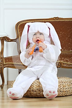 Little boy in costume bunny sitting on pouf with photo