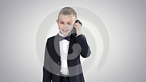 Little boy in a costume making a phone call while walking on gradient background.