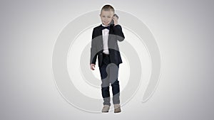 Little boy in a costume making a phone call while walking on gradient background.