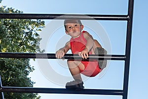 The little boy crosses high obstacles on the children`s playground