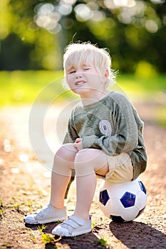 Little boy crying after fall during soccer/football game on summer day