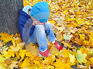 Little boy crying sitting by a tree.  children`s fear.