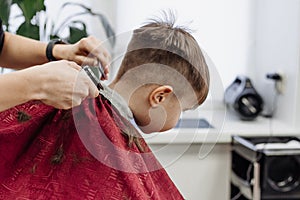 Close-up of woman hands grooming kid boy hair in barber shop