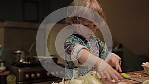 A little boy cuts an cabbage in the kitchen