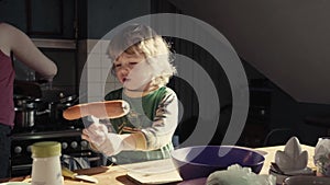 A little boy cuts an carrot in the kitchen