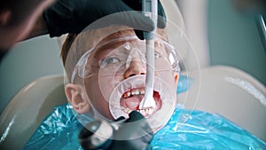 A little boy with damaged baby teeth having a treatment in the dentistry with an opening mouth guard