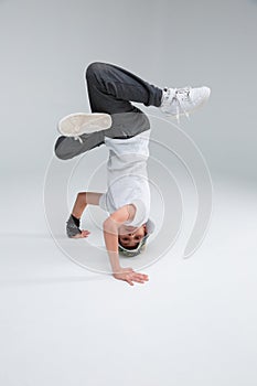 A little boy dancer break dance, stands on his head.