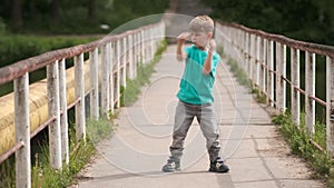 A little boy is dancing hip hop on an old iron bridge