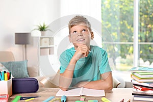 Little boy daydreaming while doing assignment