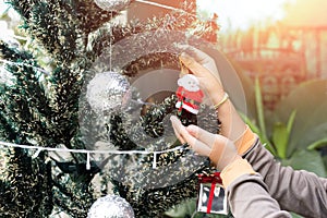 Little boy decorate Christmas tree with Santa Claus dolls decoration