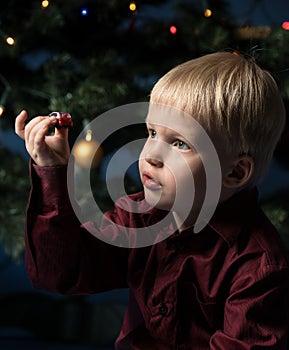 Little boy decorates the Christmas tree. Spruce with decorations. Kid and adornment