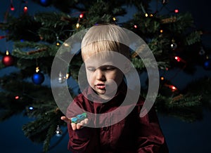 Little boy decorates the Christmas tree. Spruce with decorations. Kid and adornment