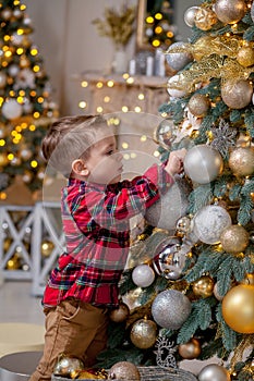 Little boy decorating Christmas tree with toy balls