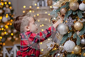 Little boy decorating Christmas tree with toy balls