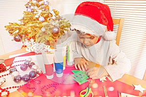 Little boy decorating paper Christmas tree