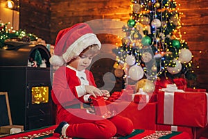 Little boy decorating xmas tree and opening gifts. New Year. Christmas time. Elf child. Winter shopping sale. New Year