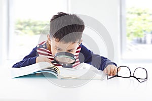 Little boy detective searching clues from books