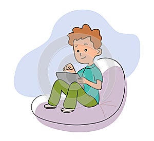 Little boy with digital tablet sitting on soft bag