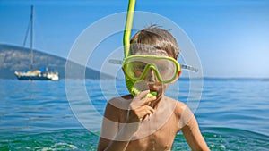 Little boy diving and jumping out of the sea water next to the beach during summer holidays