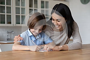 Little boy do schoolwork with Asian female tutor at home