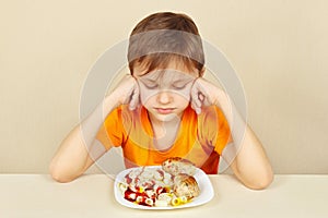 Little boy does not want to eat pasta with cutlet