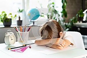 Little boy doing homework at home at the table, overwork of a first-grader from studying, stress of a schoolboy