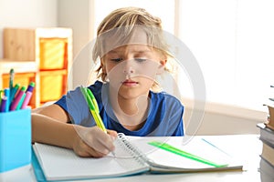 Little boy doing homework at table indoors