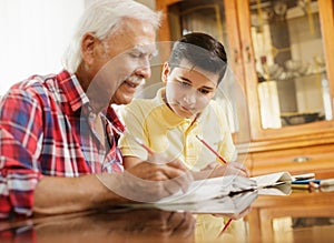 Little Boy Doing School Homework With Old Man At Home