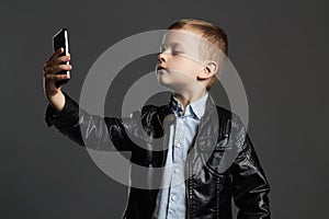 Little boy doing selfie. stylish child in leather coat and hat. kids emotion