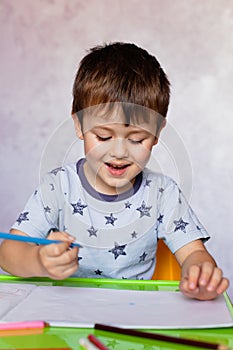 Little boy drawing with color pencils. Boy, drawing a picture for fathers day. Small boy draws at the table