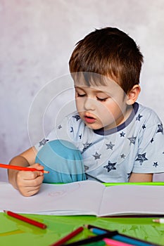 Little boy drawing with color pencils. Boy, drawing a picture for fathers day. Small boy draws at the table