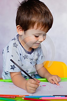 Little boy drawing with color pencils. Boy, drawing a picture for fathers day. Small boy draws at the table