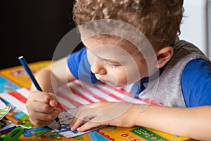 Little boy draws a USA flag. The boy colors the flag with crayons. Education, the study of state symbols, a photo