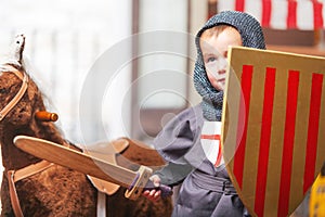 Little boy dressed as a knight playing with sword and shield