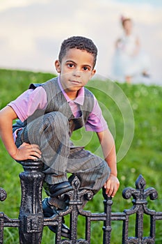 Little boy dressed in suit with vest sits on black