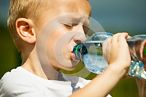Little boy drink water from bottle, outdoor