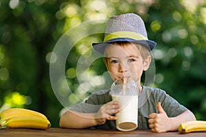 little boy drinking banana milkshake from disposable plastic glass