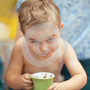 Little boy is drinking a cocoa with a mischievous expression.