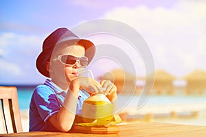 Little boy drinking coconut cocktail on tropical