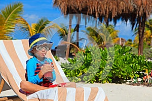Little boy drinking juice on tropical beach