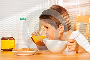 Little boy drinking orange juice at breakfast