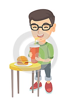 Little boy drinking soda and eating cheeseburger.